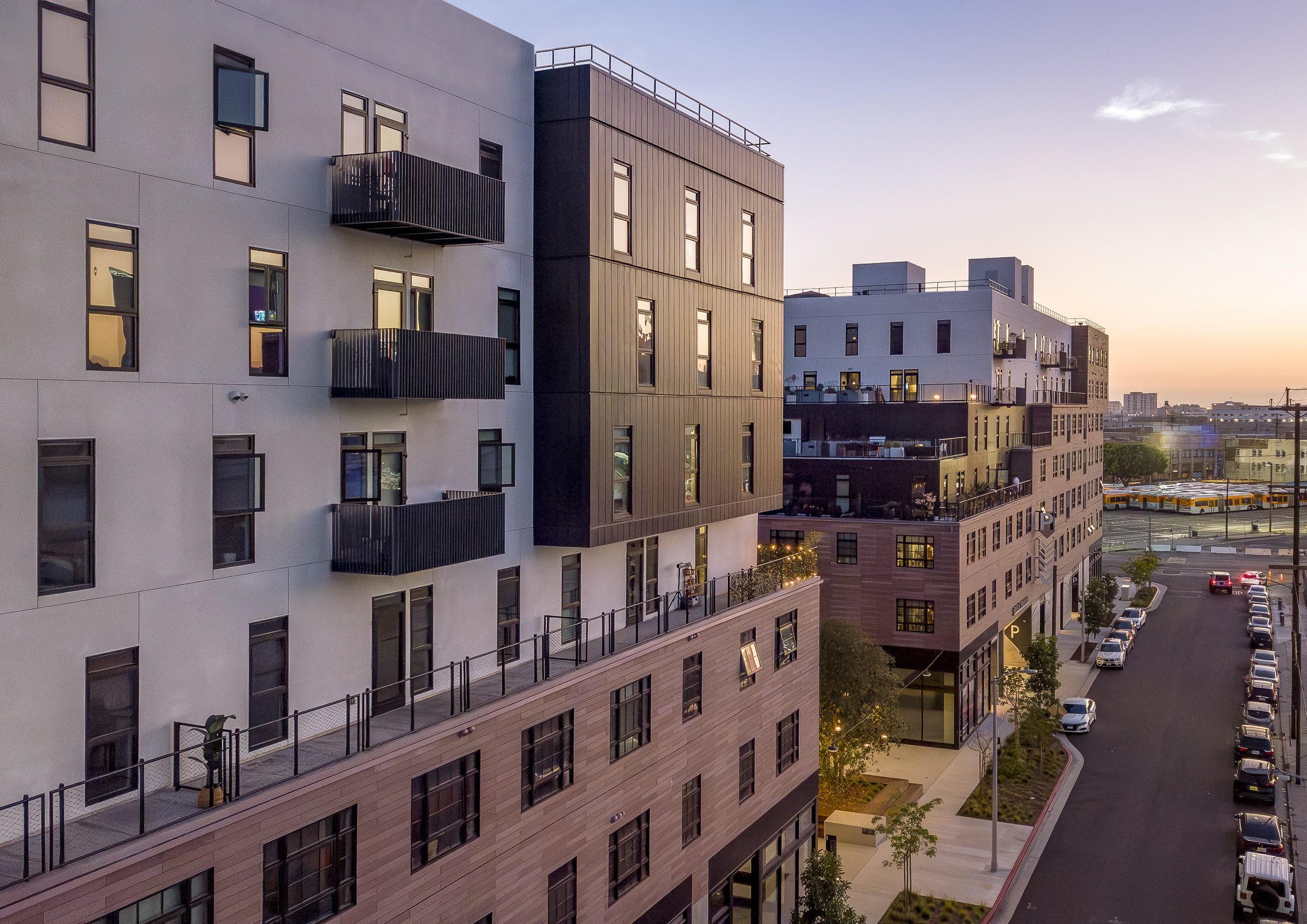 Exterior view of AVA LA Arts District live/work apartments with balconies and stepped terraces at sunset.