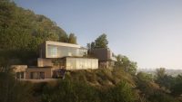 Glass and stone residence stepping down a wooded hillside.