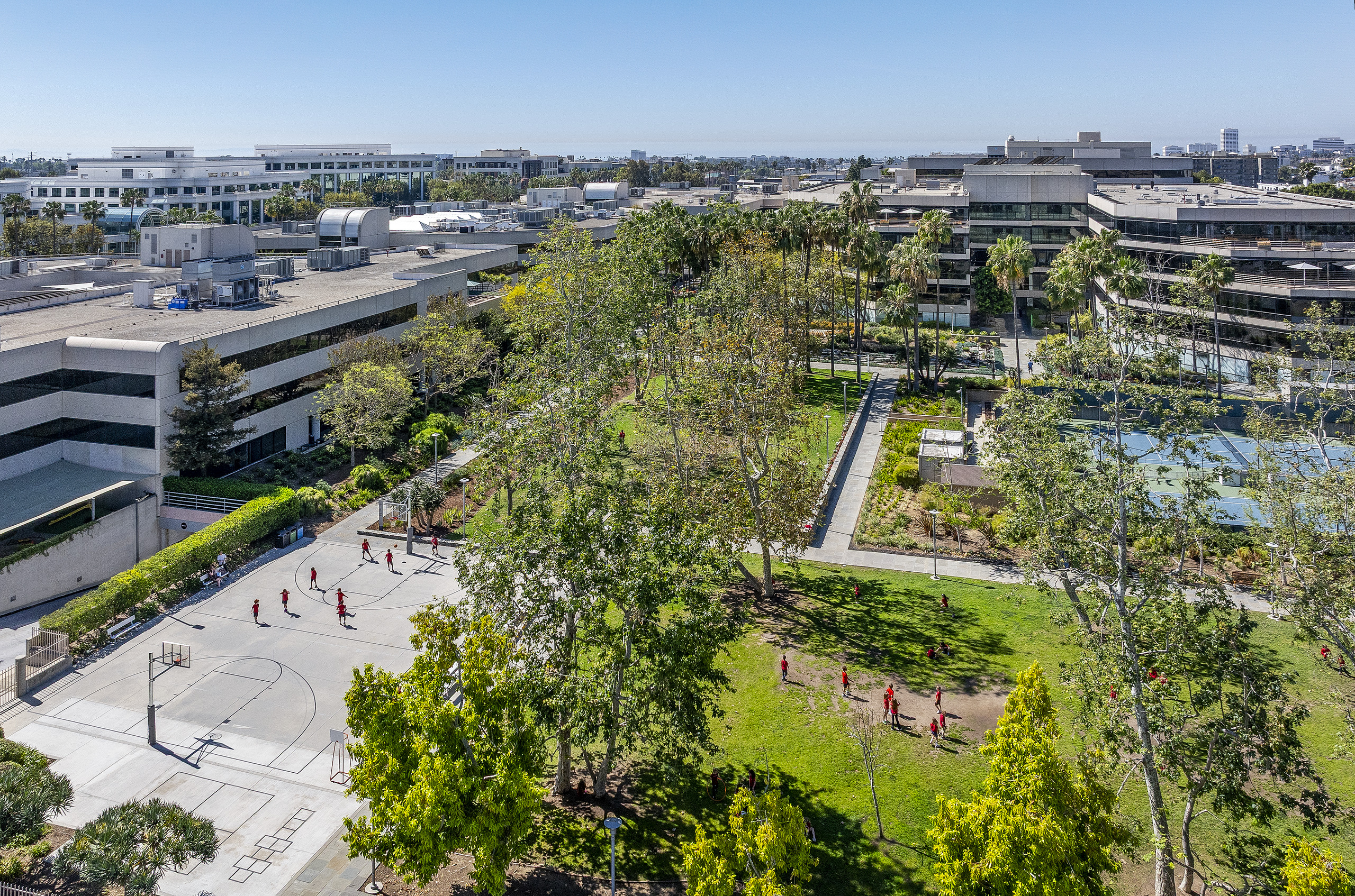 Aerial view of children playing on basketball courts and a landscaped lawn at Village School in Santa Monica.