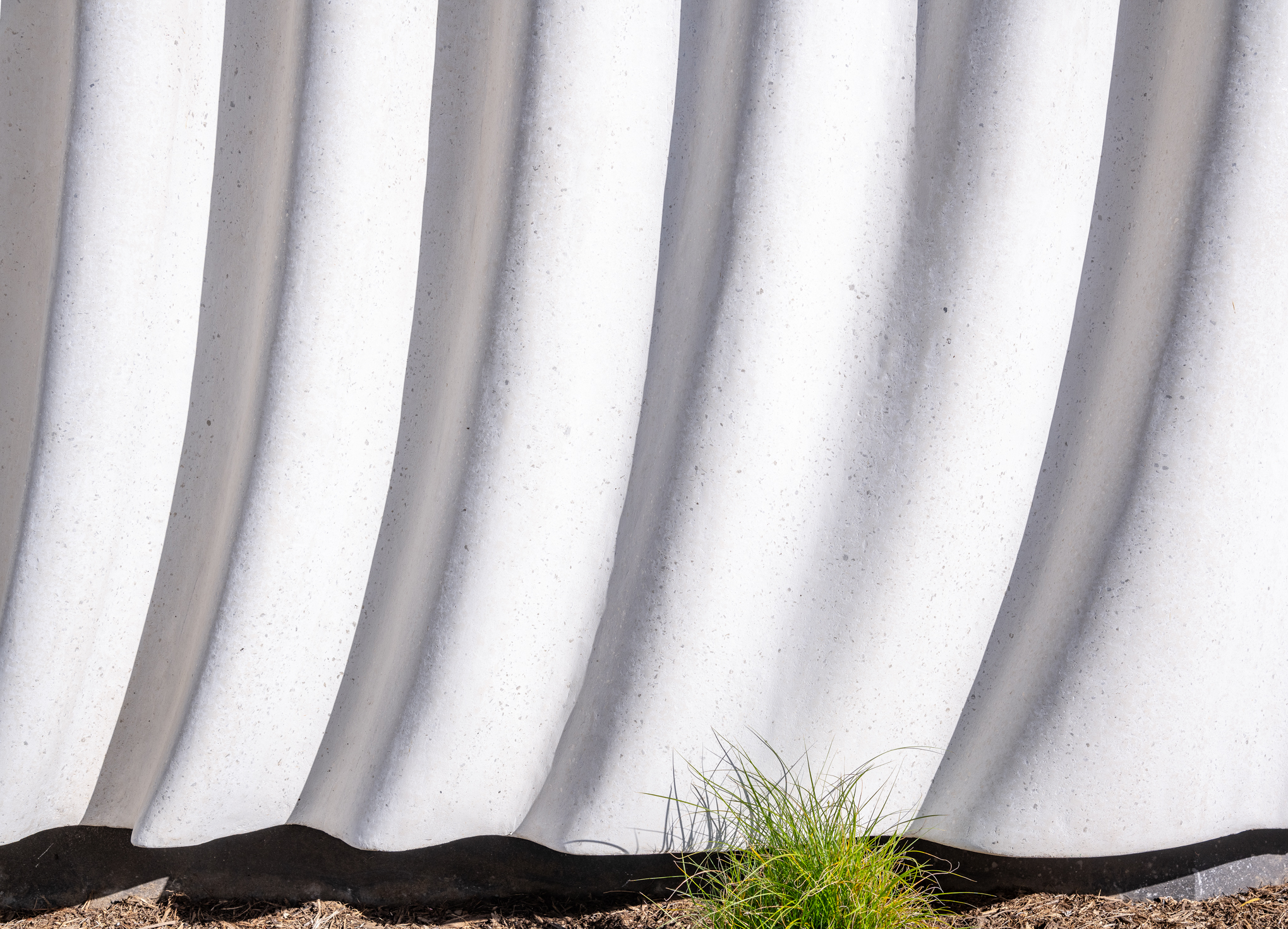 Detail of the textured mica-infused plaster façade at the SNAP Campus amenity building designed by OFFICEUNTITLED.